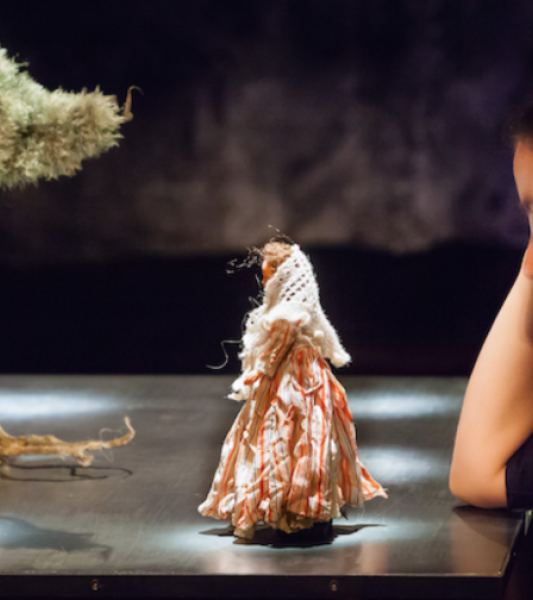 une femme en fichu regarde une figurine de femme devant un arbre